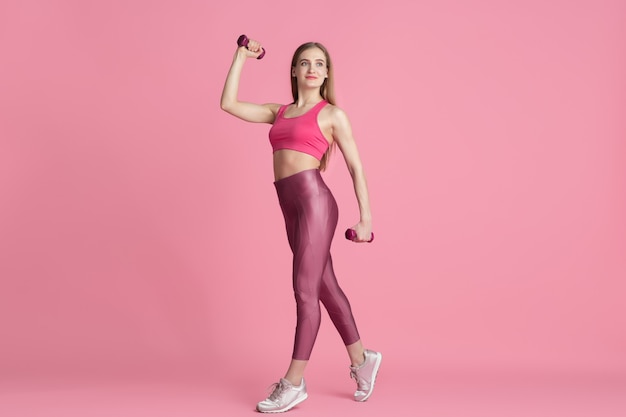 Vertrouwen. Mooie jonge vrouwelijke atleet beoefenen, zwart-wit roze portret. Sportief fit Kaukasisch model met gewichten. Body building, gezonde levensstijl, schoonheid en actie concept.