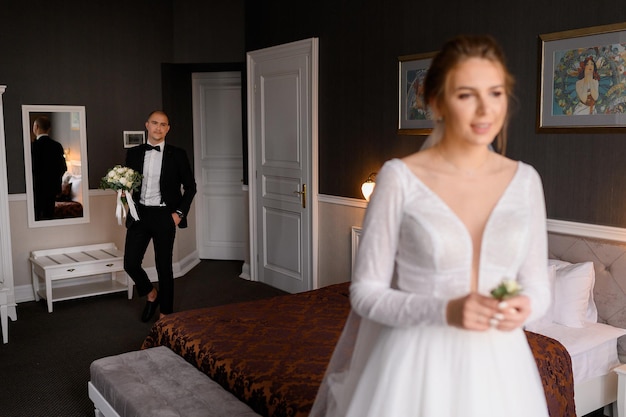 Gratis foto vervagen van een aantrekkelijke bruid in een elegante jurk die een huwelijksknoopsgat vasthoudt en wacht op een ontmoeting met haar bruidegom in een hotelappartement terwijl