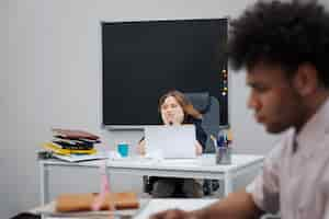 Gratis foto verveelde vrouw zit aan bureau