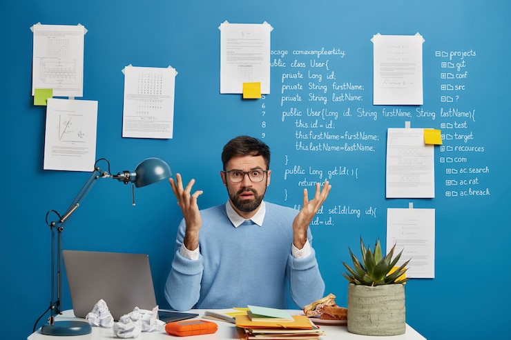 Gratis Foto verward bebaarde man steekt handen met verbazing, werkt freelance