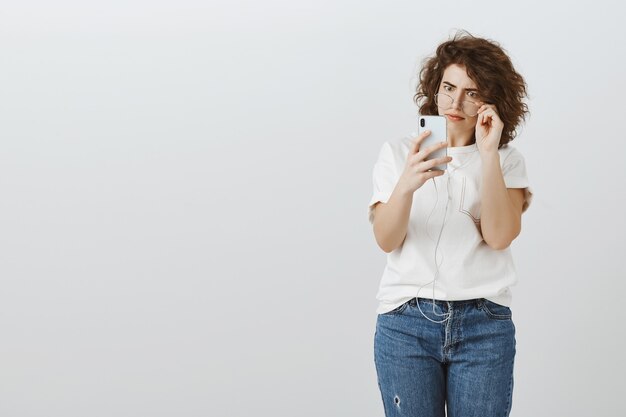 Verward en geschrokken vrouw die geschokt kijkt naar het scherm van de mobiele telefoon