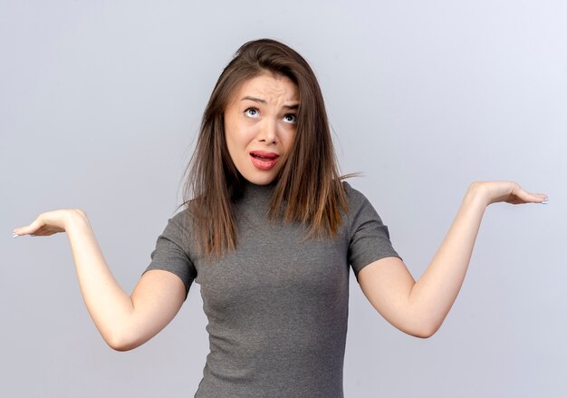 verward jonge mooie vrouw opzoeken en lege handen tonen op wit wordt geïsoleerd