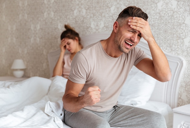 Verwarde bezorgde man zittend op bed met zijn vriendin
