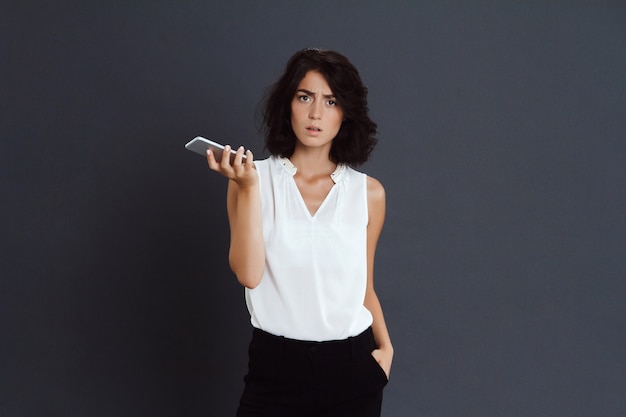 Verwarde jonge vrouw die haar telefoon in handen houdt