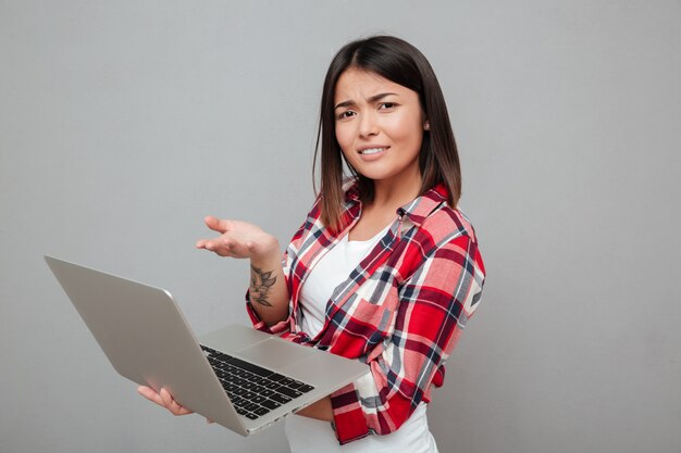 Verwarde jonge vrouw die laptop computer met behulp van.