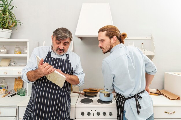 Verwarde vader en zoon die in een kookboek kijken