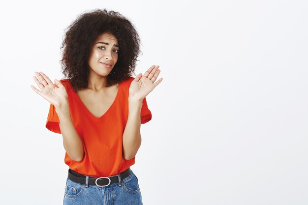 verwarde vrouw met afro kapsel poseren in de studio