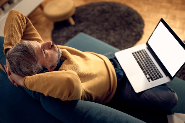 Verwarde zakenman die denkt terwijl hij thuis laat op een laptop werkt