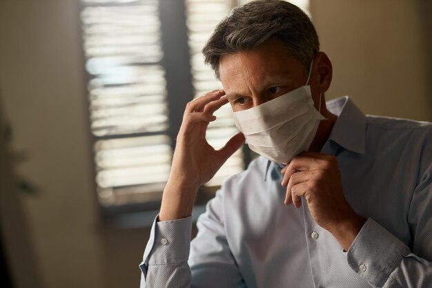 Verwarde zakenman met een gezichtsmasker die op kantoor werkt tijdens een virusepidemie