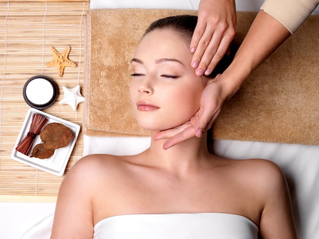 Verwennerij en massage voor mooi gezicht van jonge vrouw in spa salon
