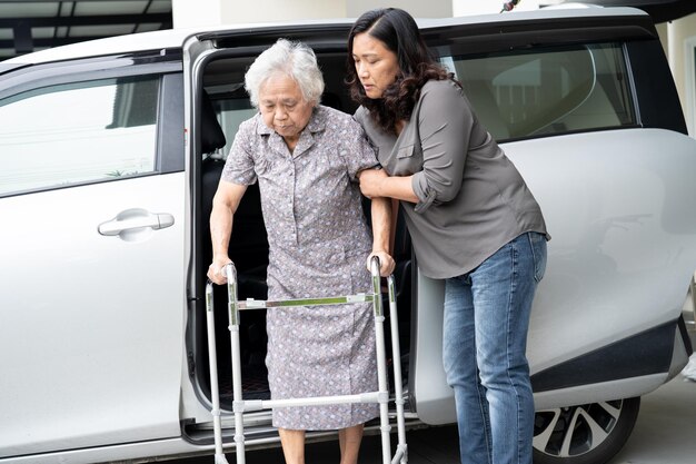 Verzorger dochter helpt en ondersteunt aziatische senior of oudere oude dame vrouw patiënt bereidt zich voor om uit haar auto te stappen.