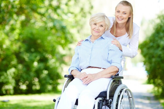 Verzorger duwen hooggeplaatste vrouw in rolstoel