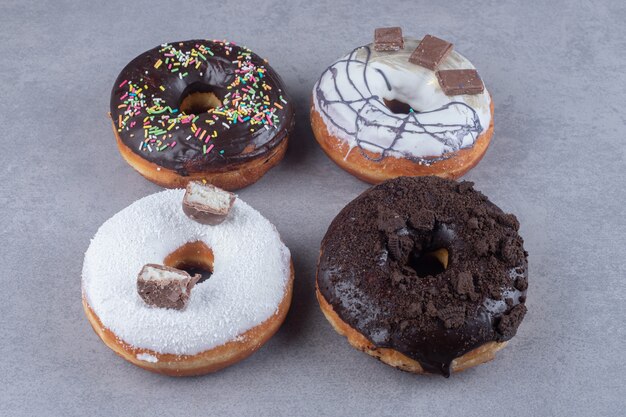 Vier donuts met verschillende toppings op marmeren ondergrond