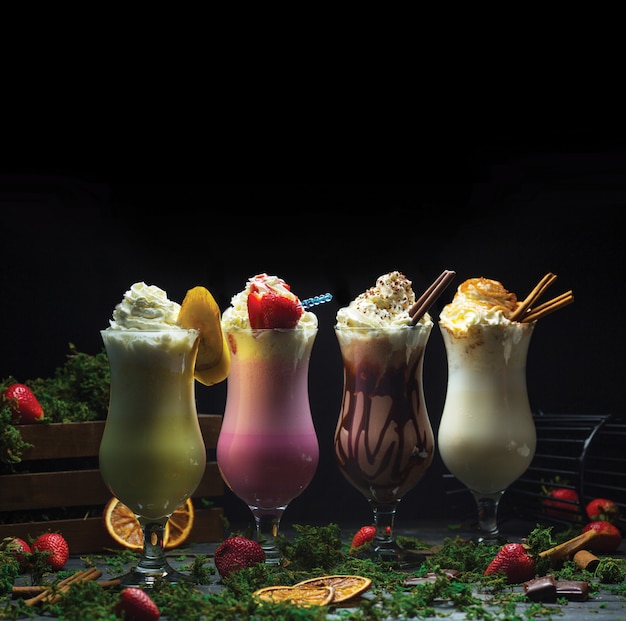 Vier verschillende cocktail smoothies met melkachtige crème bovenop