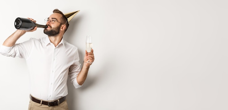 Gratis Foto viering en vakantie man chamapgne drinken uit fles op verjaardagsfeestje staande tegen wit