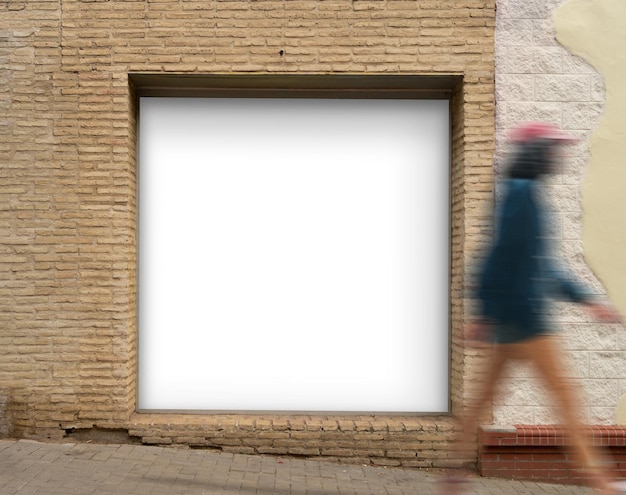 Gratis foto vierkante witte poster in bakstenen nis in straat met wandelende persoon