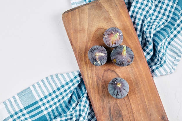 Vijgen op een houten bord met een blauw tafelkleed.