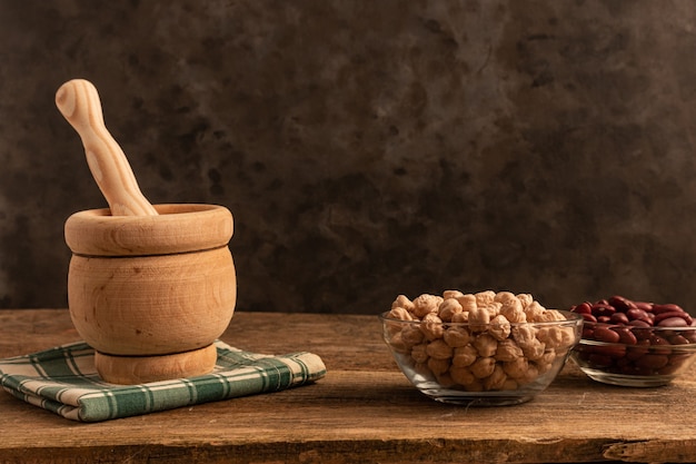 Vijzel met stamper van hout, 3 bakjes kikkererwten, rode bonen, linzen op tafel