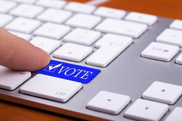 Vinger op stem blauwe knop en symbool op toetsenbord te drukken. online verkiezingen