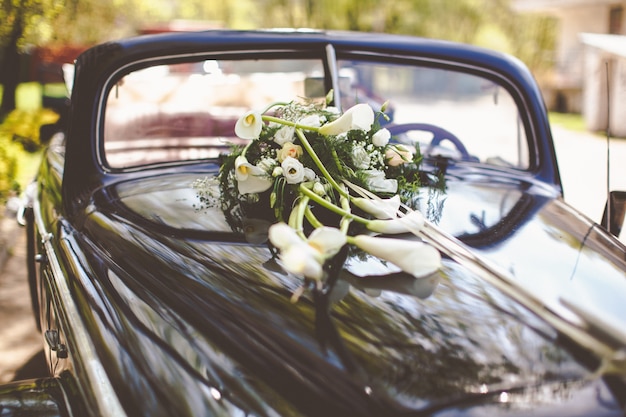 Vintage zwarte auto versierd met callas voor een trouwreisje