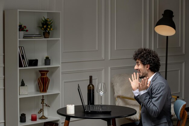 Virtuele liefde knappe schattige kerel in een pak met wijn op een afstand computer date opgewonden zwaaiende handen