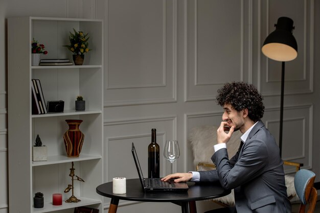 Virtuele liefde knappe schattige kerel in een pak met wijn op een afstand computer datum bijtende vinger