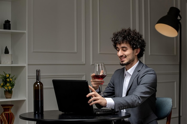 Virtuele liefde knappe schattige kerel in pak met wijn op een computerdatum op afstand met rode wijnglas