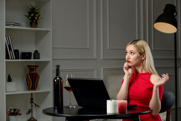 Virtuele liefde schattig blond meisje in rode jurk op afstand datum met wijn opzoeken