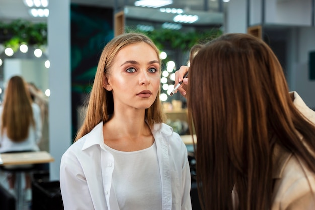 Gratis foto visagiste doet make-up voor de vrouw