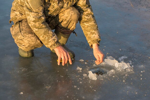 Vissen in het riet om te spinnen op rustig water een man in camouflagekleding bij koud weer