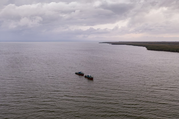 Gratis foto vissersboten, drijvend in de kalme wateren en gaan vissen onder een hemel met wolken