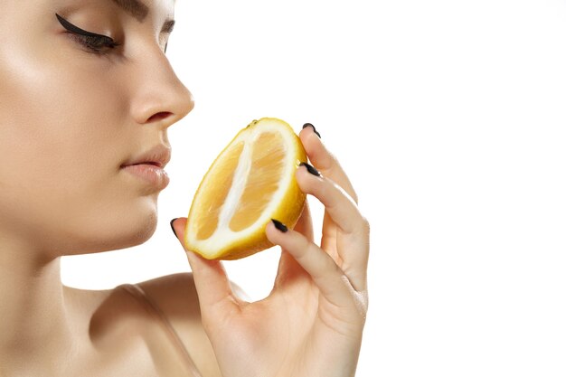 Vitaminen. Close up van mooie jonge vrouw met sappige schijfjes citroen op white