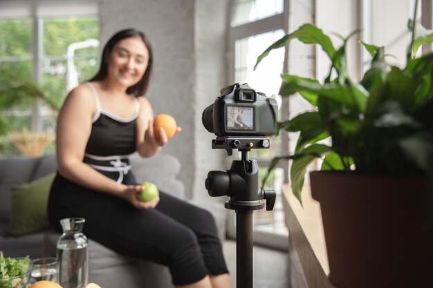 Vitaminen. Kaukasische blogger, vrouw maakt vlog over diëten en afvallen, lichaamspositief zijn, gezond eten. Met behulp van camera die haar fruitsalade voorbereidt.