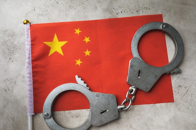 Vlag van china en handboeien op een abstracte achtergrond, het concept van misdaad in de chinese samenleving