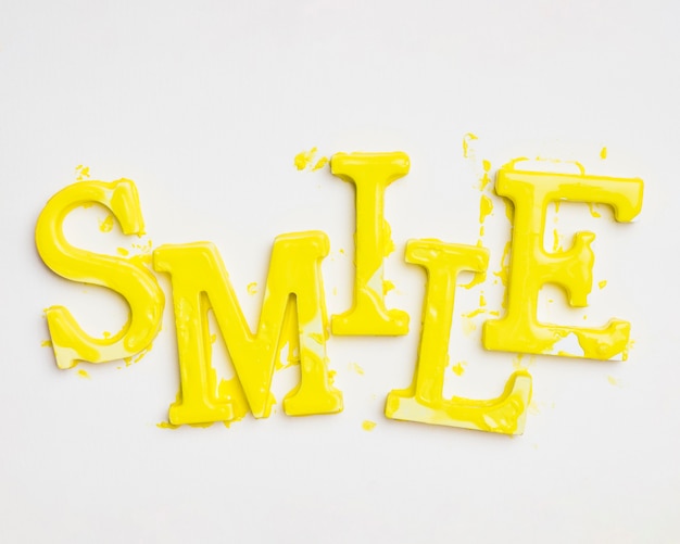 Gratis foto vlak leg van woordglimlach met verf