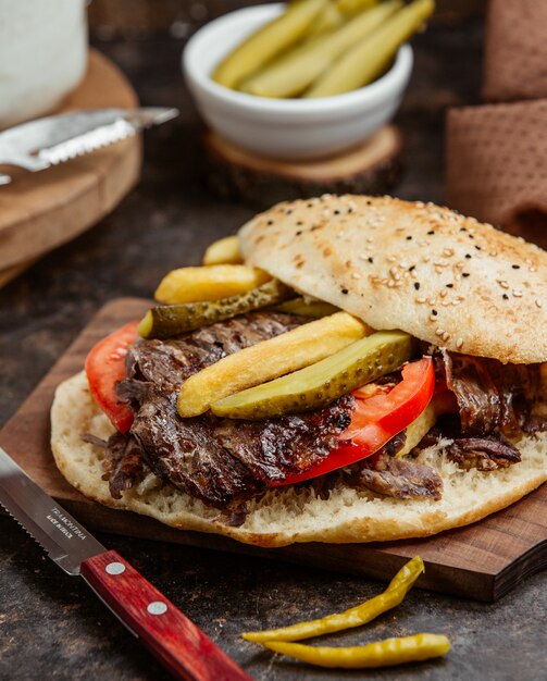 Vleesdoner met gemarineerde pickels en tomaat in brood.