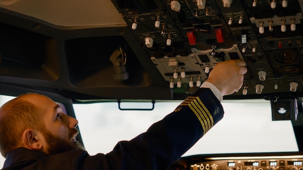 Gratis foto vliegtuigkapitein startmotor met aan / uit-knoppen op dashboard om vliegtuig vanuit cockpit te vliegen. schakelaar en hendel indrukken om op te stijgen, met behulp van het bedieningspaneel met kompas op de voorruit.