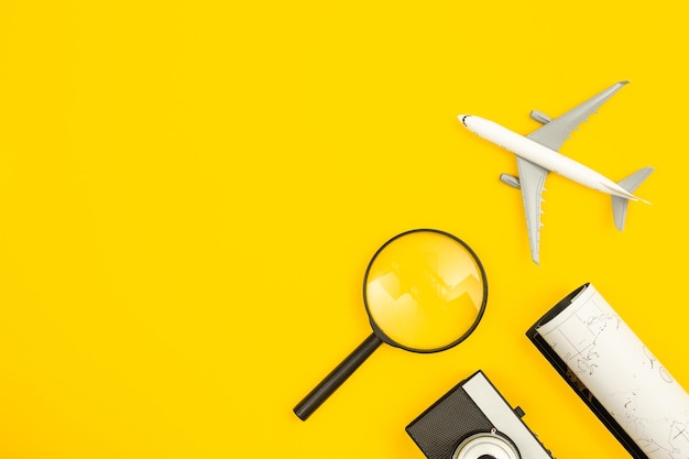 Vliegtuigmodel kaart en vergrootglas op gele achtergrond plat leggen