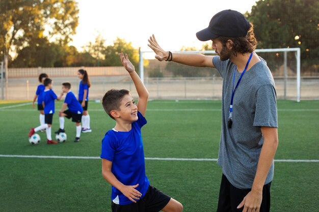 Voetbaltrainer feliciteren met kind zijaanzicht