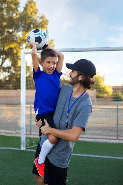 Gratis foto voetbaltrainer met zijaanzicht van het kind