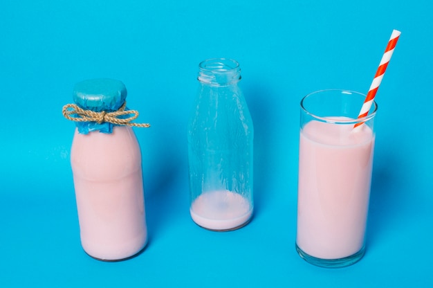 Gratis foto vol glas roze smoothie naast lege en volle flessen