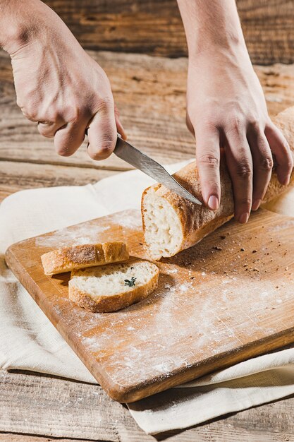 Volkorenbrood op keuken houten plaat gezet met een chef-kok die gouden mes houdt om te snijden.