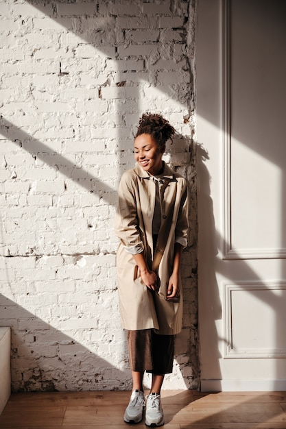 Volle lengte weergave van lachende vrouw in trenchcoat