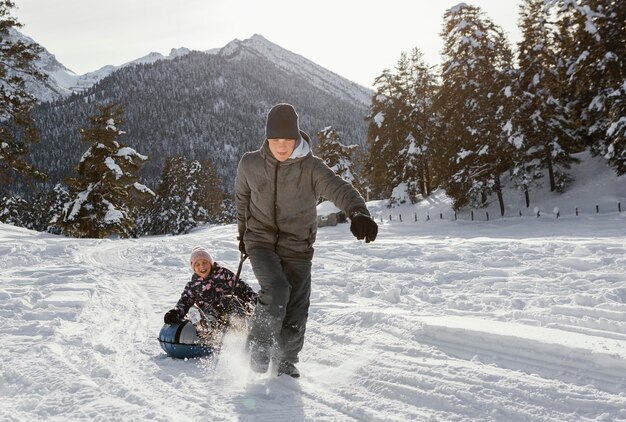 Volledig geschoten familieleden die in de sneeuw spelen