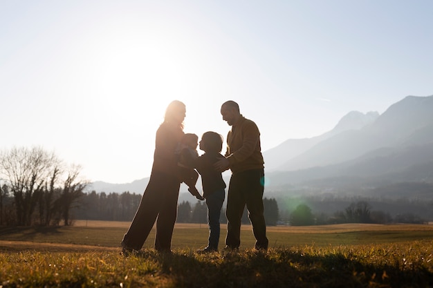 Volledig geschoten familiesilhouet in de natuur bij zonsondergang