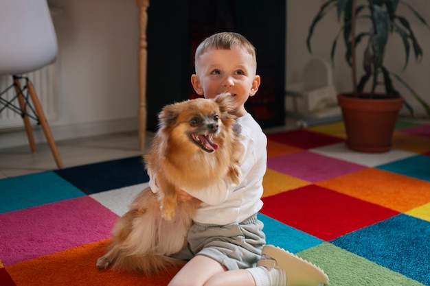 Gratis foto volledig geschoten jongen die binnen met hond speelt