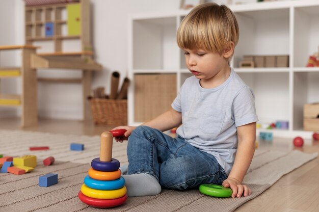 Volledig geschoten kind dat op de vloer speelt met speelgoed