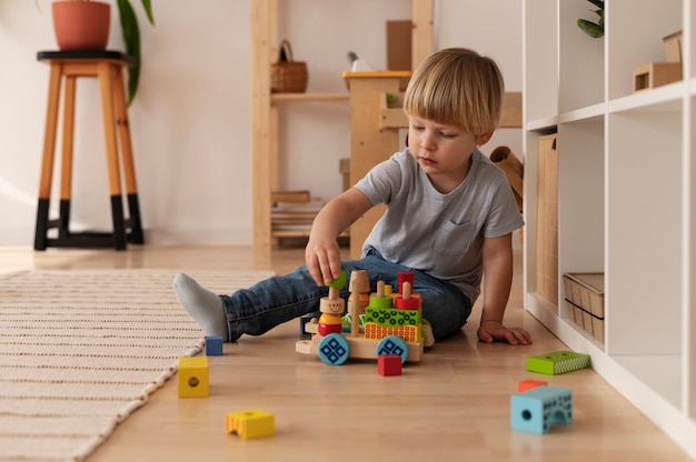 Volledig geschoten kind dat thuis met houten speelgoed speelt