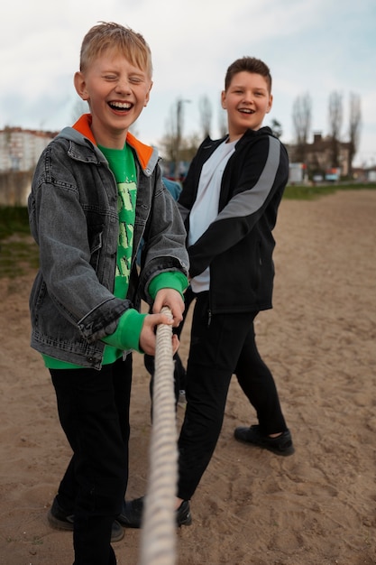 Volledig geschoten kinderen die touwtrekken spelen op het strand