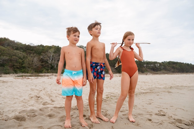 Volledig geschoten kleine kinderen die plezier hebben op het strand